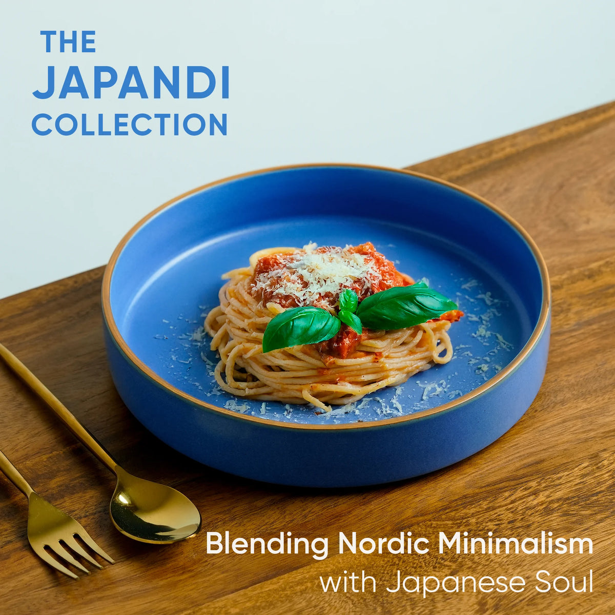 Blue plate with spaghetti and basil on a wooden table, featuring 'The Japandi Collection' text.