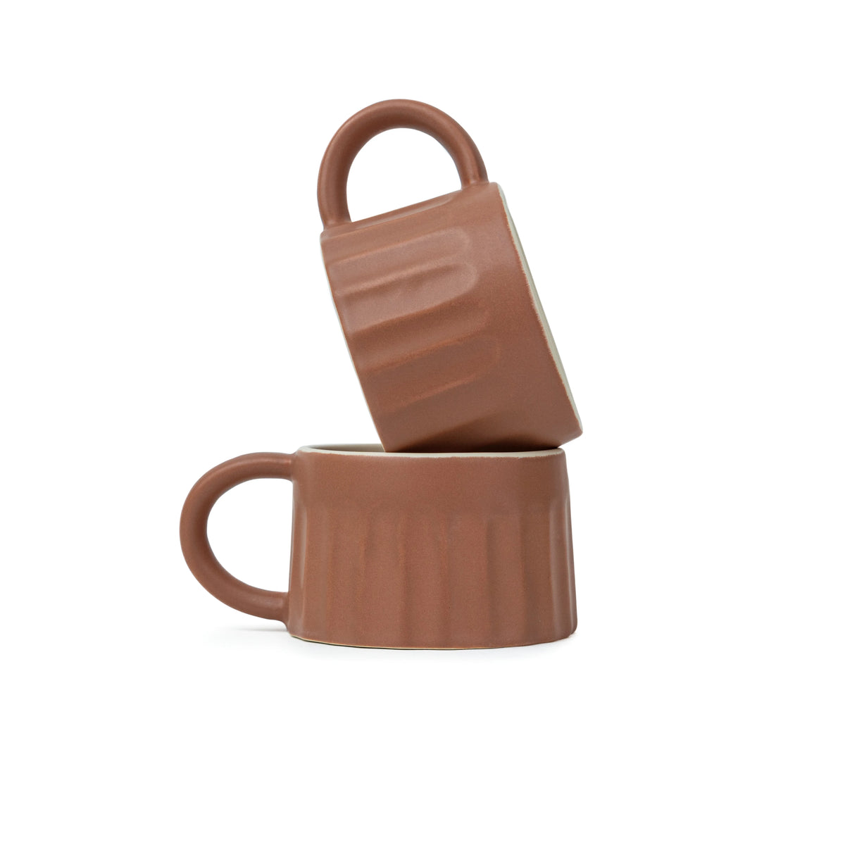 Two brown ceramic mugs stacked on a white background