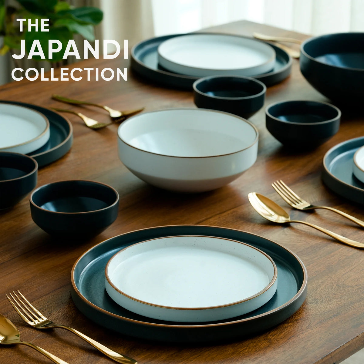 Dining table set with Japandi collection plates, bowls, and gold utensils on a wooden surface.