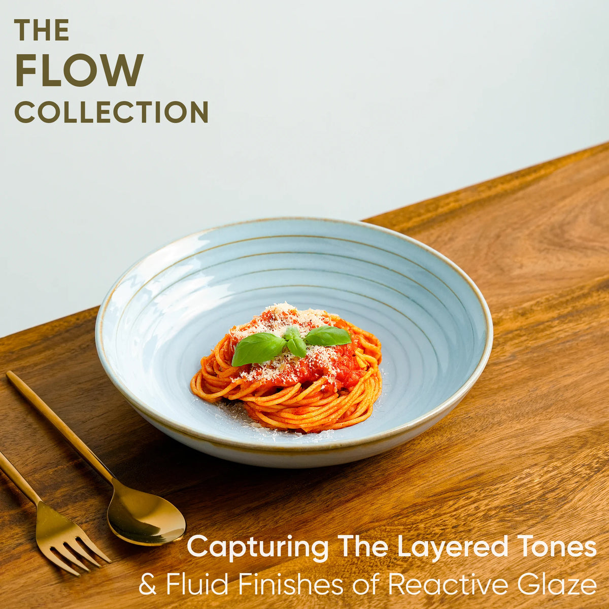 Blue ceramic plate with spaghetti on a wooden surface, featuring 'The Flow Collection' text.
