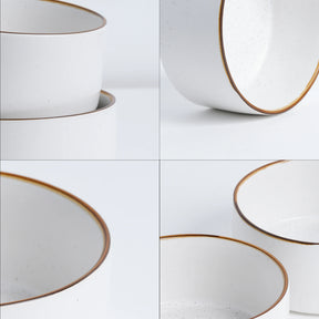Set of white ceramic bowls with gold rims on a light gray background