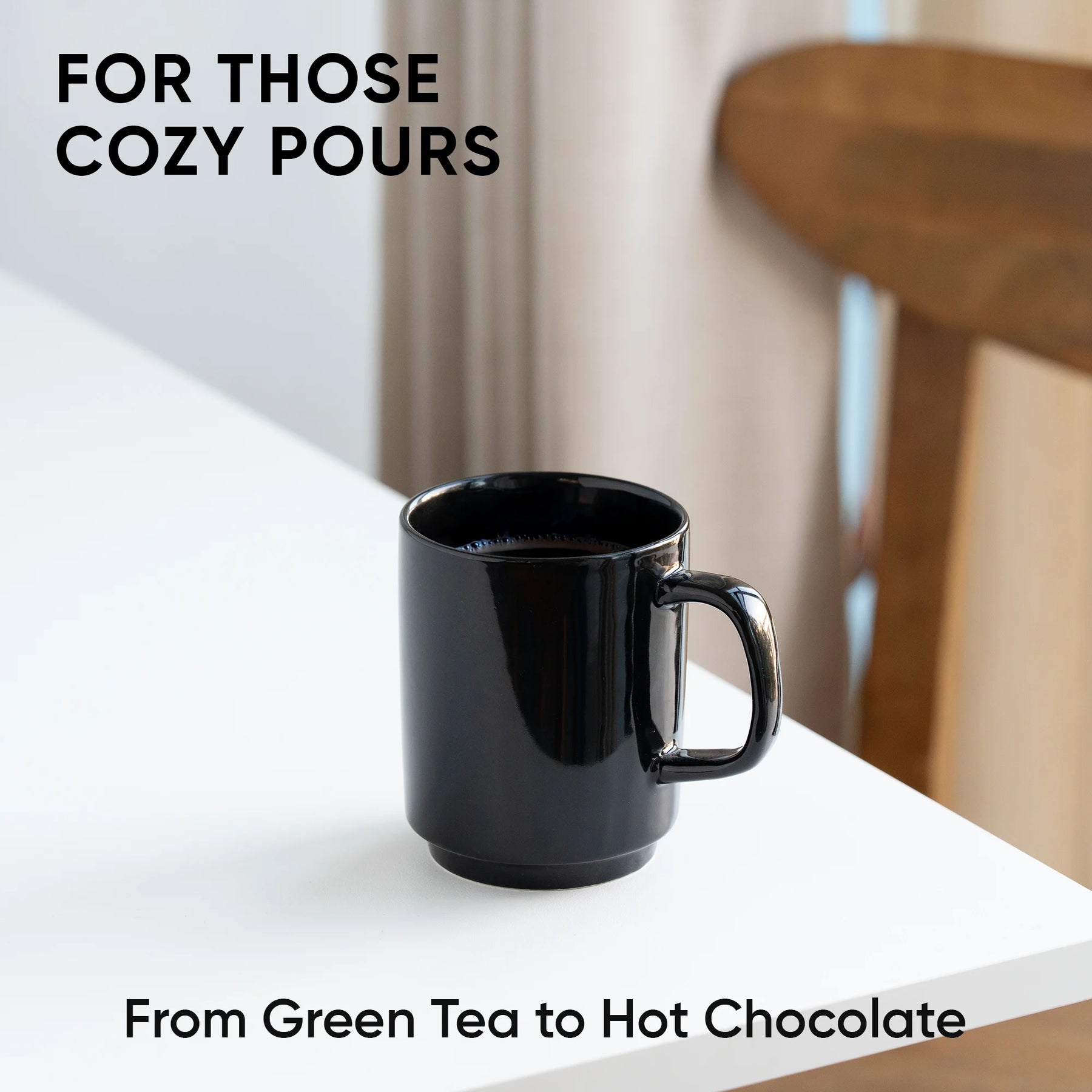 Black mug on a white surface with text about cozy pours and drink options.