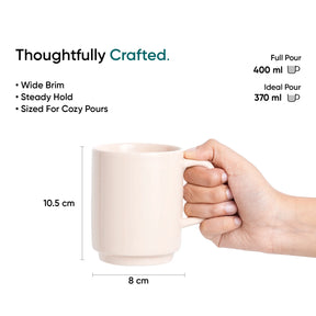 Beige mug held by a hand with measurements and text on a white background