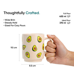 Mug with avocado design held by a hand, showing measurements and text about the mug's features.