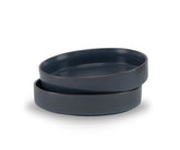 Two dark blue ceramic bowls stacked on a white background