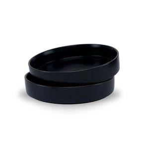 Two black ceramic bowls stacked on a white background