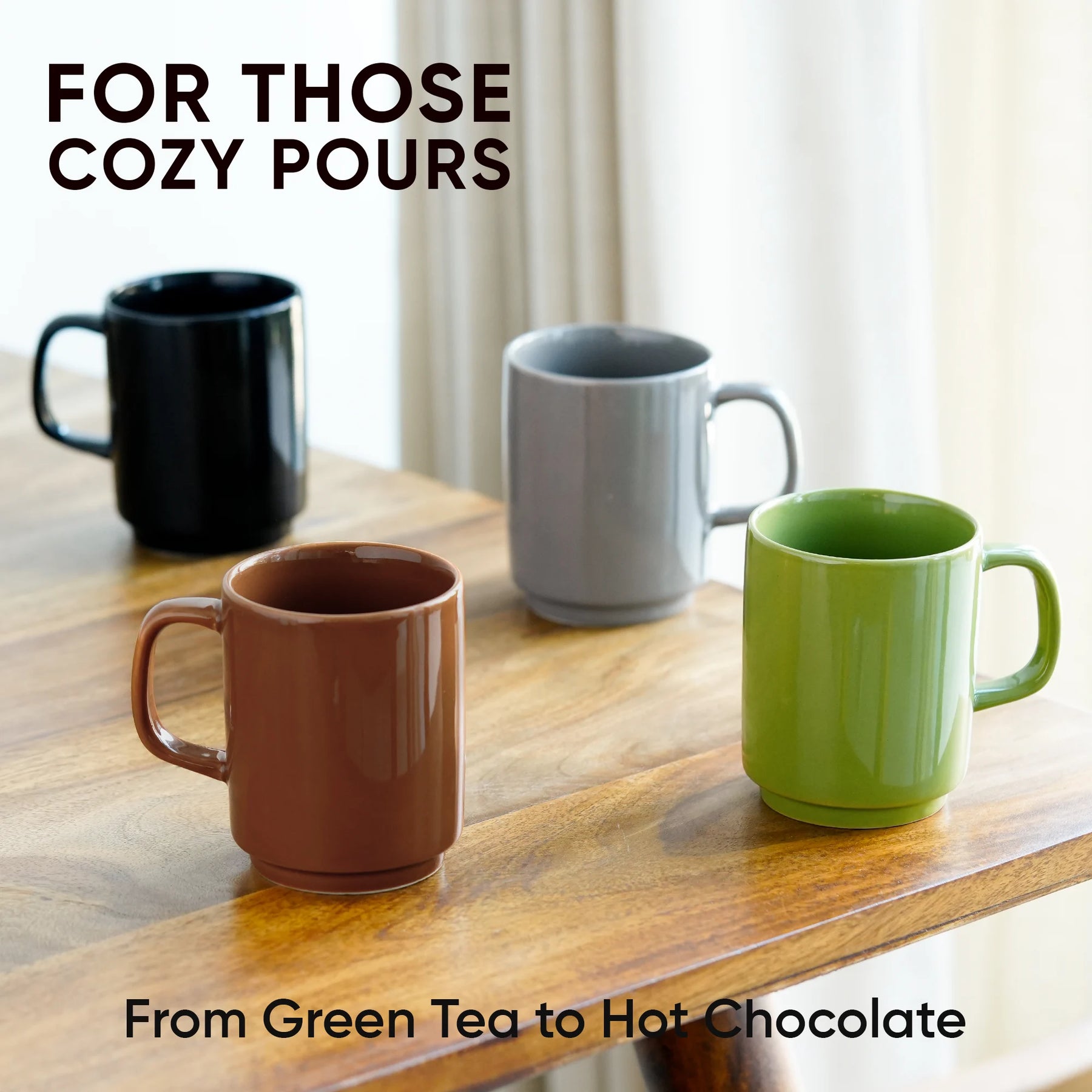 Four mugs in black, gray, brown, and green on a wooden surface with text about cozy pours.