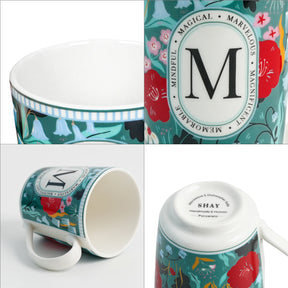 Colorful mug with floral design and decorative packaging featuring the letter 'M'.