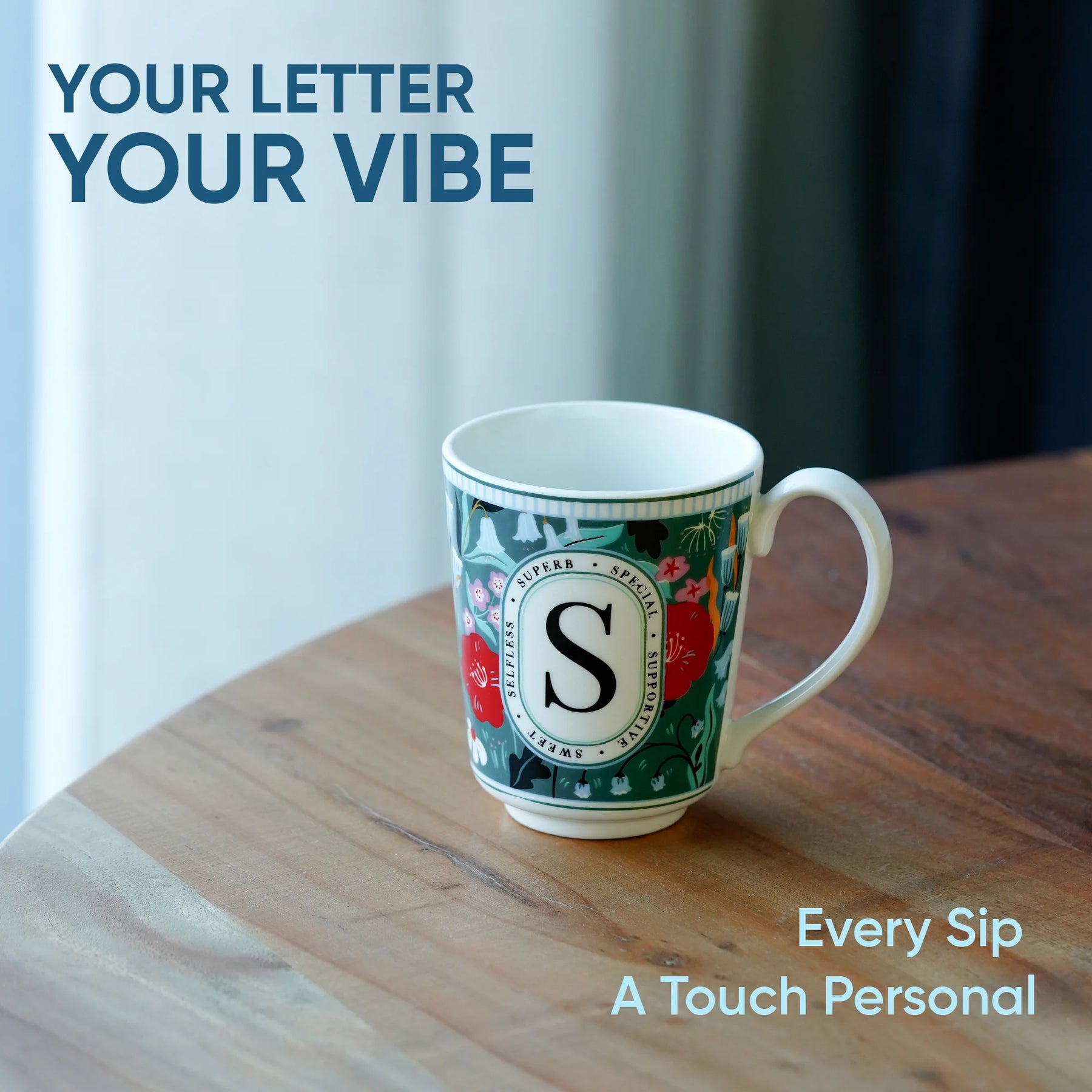 Decorative mug with letter 'S' on a wooden surface, text 'Your Letter Your Vibe' and 'Every Sip A Touch Personal' displayed.