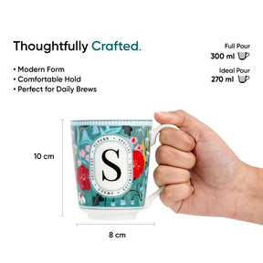 Mug with floral design and measurements, held by a hand, on a white background.