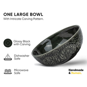 Glossy black bowl with intricate carvings on a white background