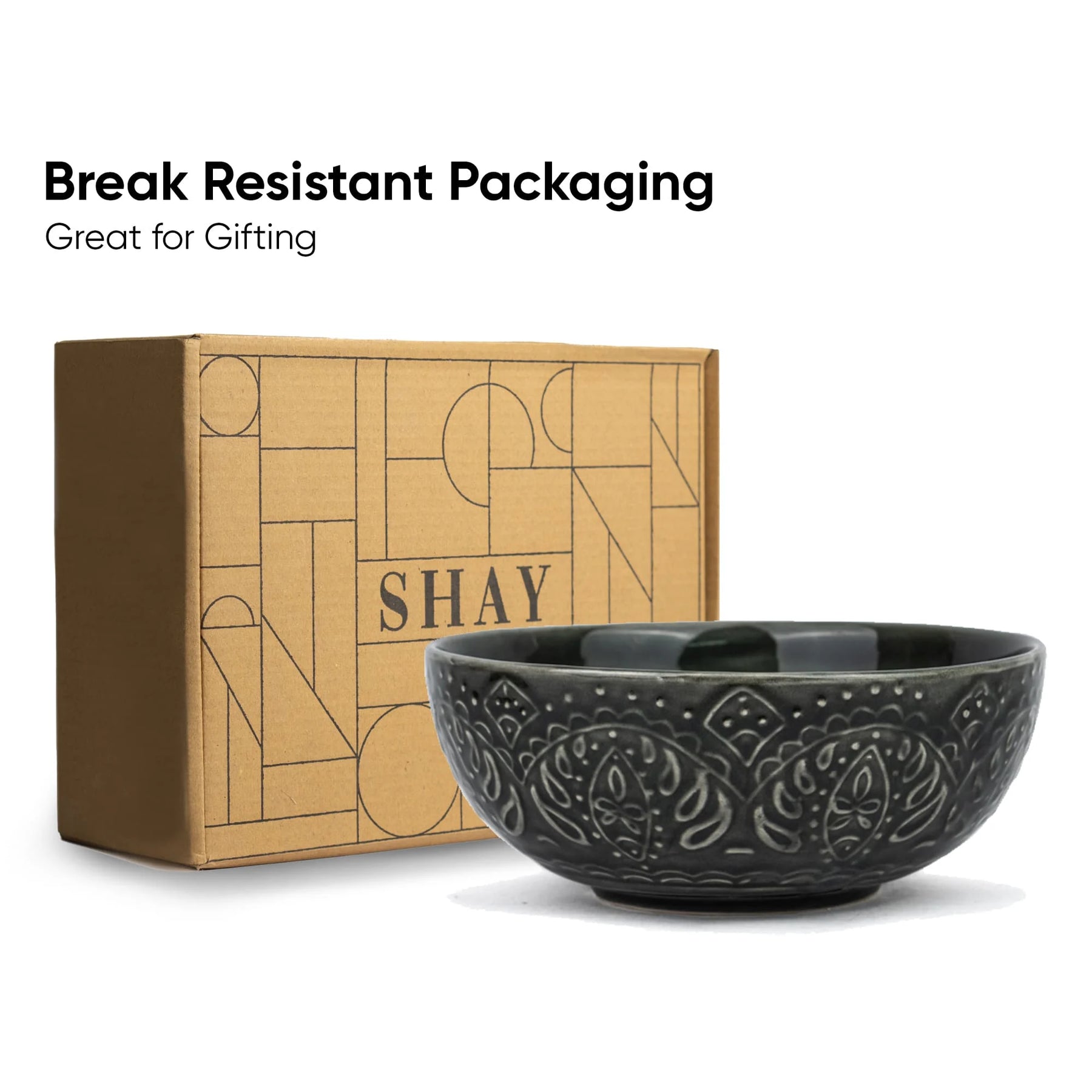Black ceramic bowl with decorative patterns next to a cardboard box labeled 'SHAY' on a white background.