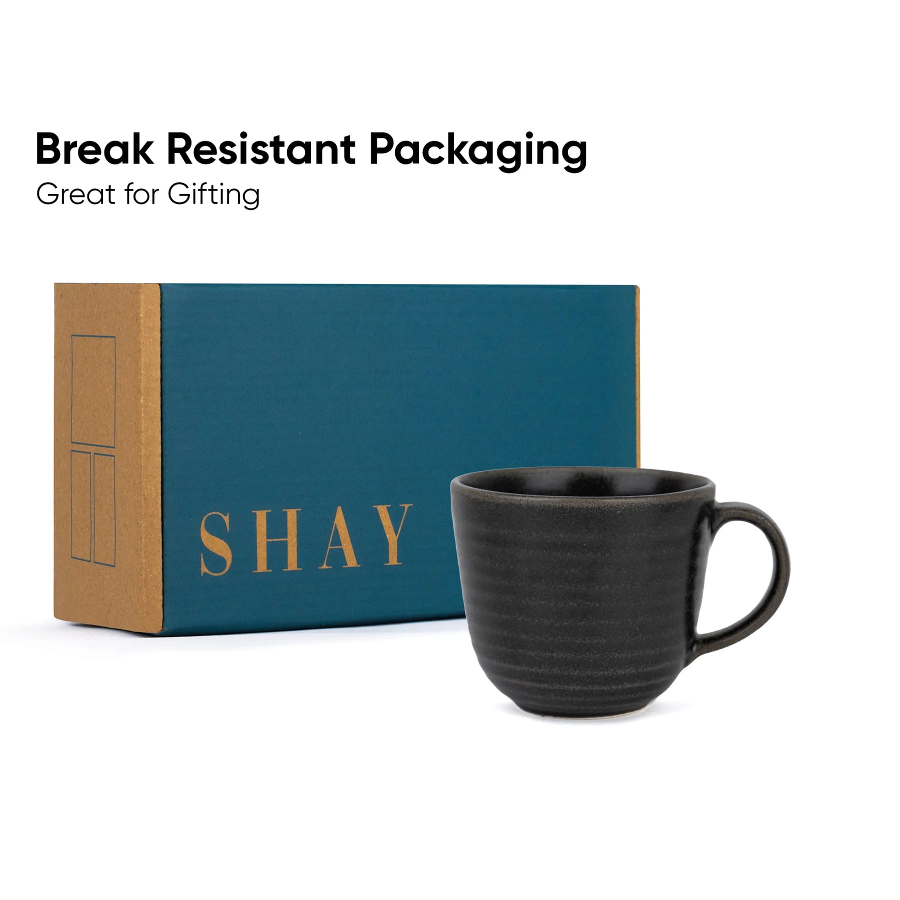 Black mug with 'SHAY' branding in front of a teal and brown box, on a white background.