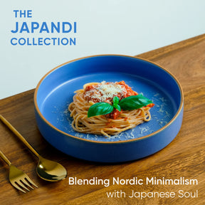 Blue plate with spaghetti and basil on a wooden table, featuring 'The Japandi Collection' text.