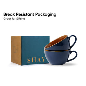 Two navy blue cups with gold interior and handles on a teal box labeled 'SHAY'. Text 'Break Resistant Packaging Great for Gifting' above.