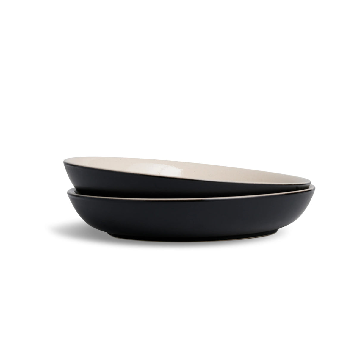 Two black bowls with beige interiors on a white background