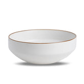 White ceramic bowl with a gold rim on a white background