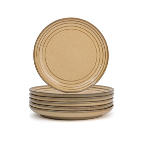 Set of four beige ceramic plates stacked on a white background