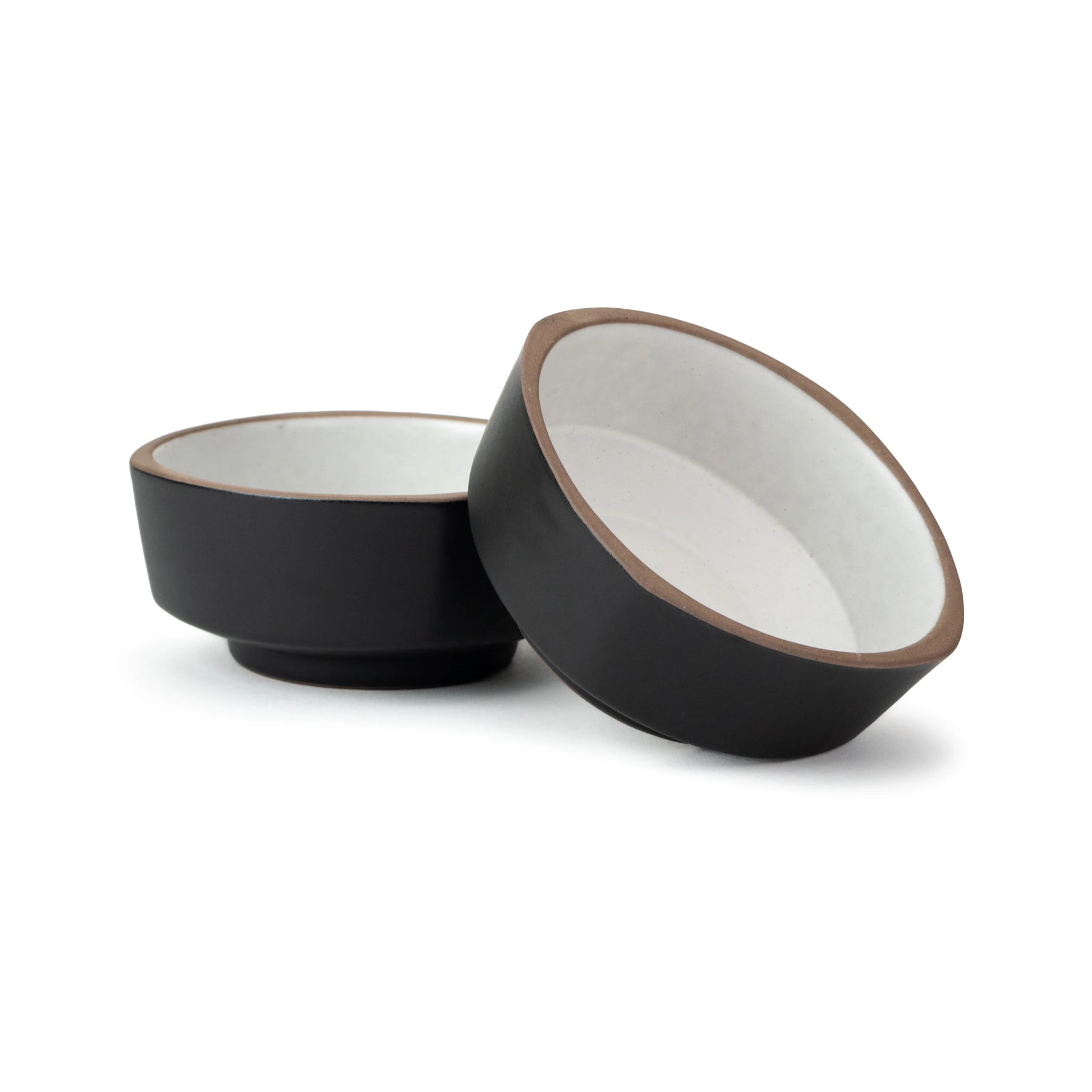 Two black ceramic bowls with white interiors on a white background