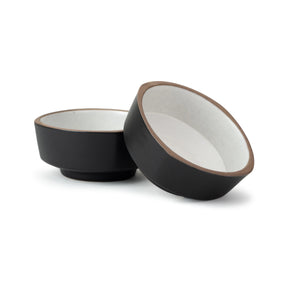 Two black ceramic bowls with white interiors on a white background