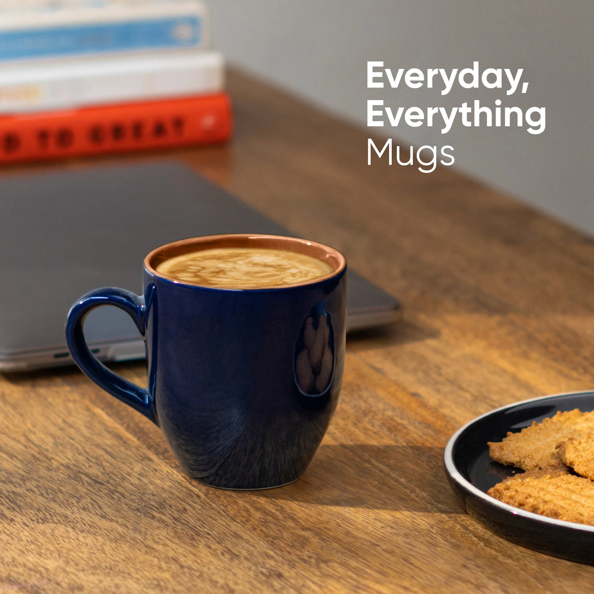 Blue mug with coffee and cookies on a wooden table, with 'Everyday, Everything Mugs' text.