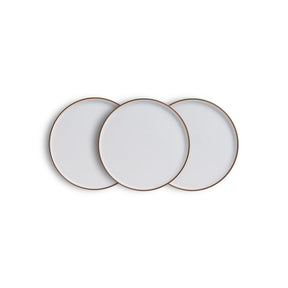 Three white ceramic plates with gold rims on a white background