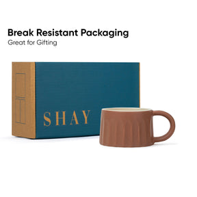 Brown mug with 'SHAY' branding next to a teal box, labeled 'Break Resistant Packaging'.