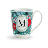 Decorative mug with floral design and letter 'M' on a white background