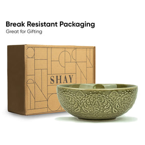 Ceramic bowl with 'SHAY' branding next to a cardboard box, with text about break-resistant packaging.