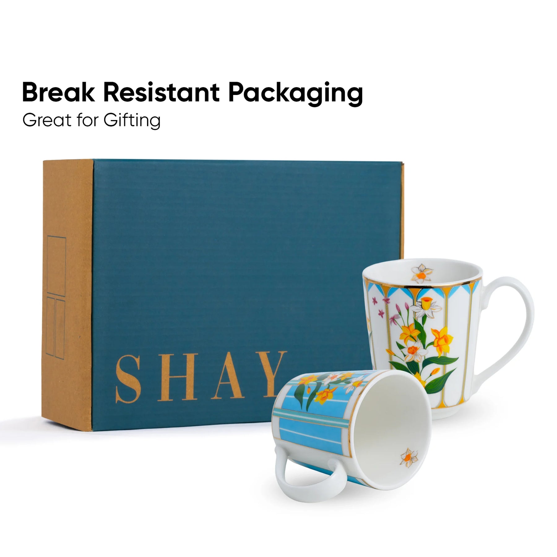 Two floral mugs with 'SHAY' branding next to a blue box, labeled 'Break Resistant Packaging'.