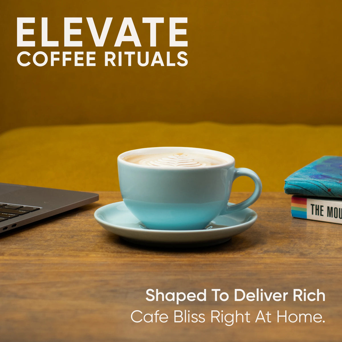 Blue coffee cup on a wooden table with a laptop and books, featuring 'Elevate Coffee Rituals' text.