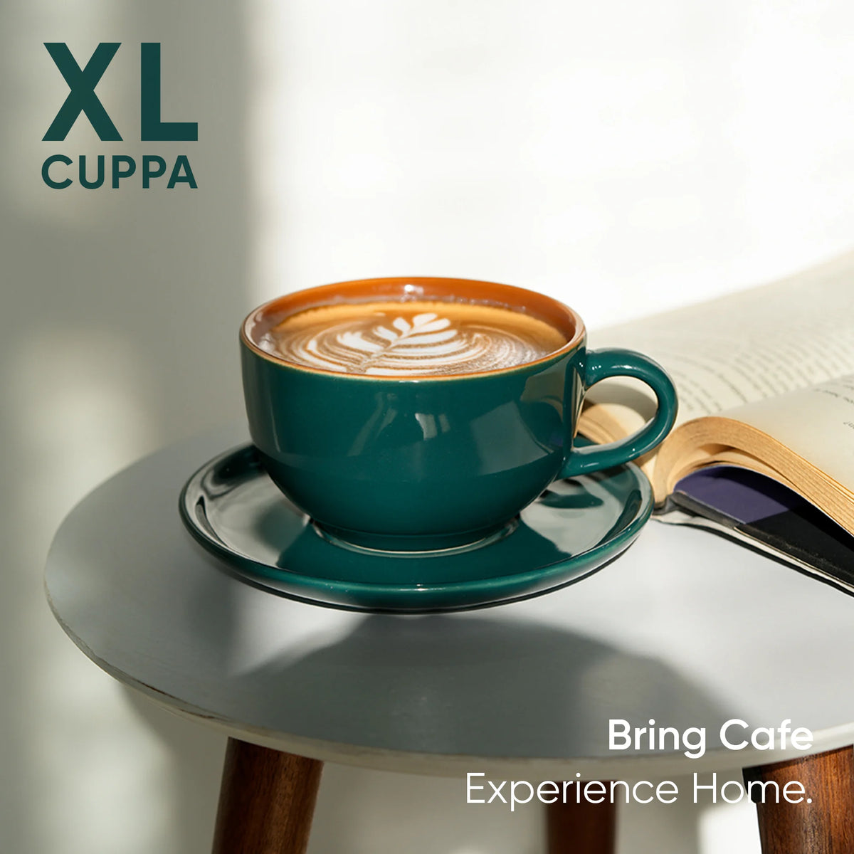 Teal coffee cup with latte art on a saucer, placed on a wooden table with an open book.