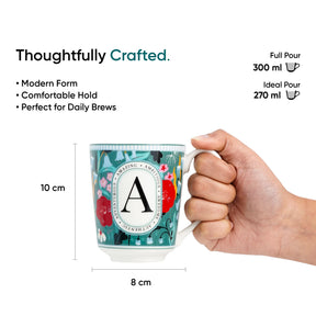 Mug with floral design and letter 'A', held by a hand, with product details on a white background.