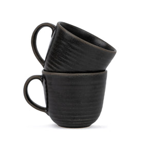 Two black ceramic mugs stacked on a white background