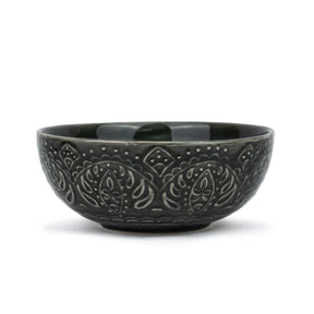 Black ceramic bowl with embossed patterns on a white background