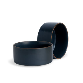 Two navy blue ceramic bowls on a white background