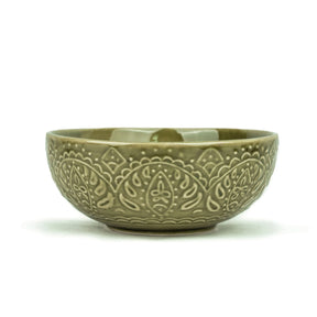 Green ceramic bowl with intricate patterns on a white background